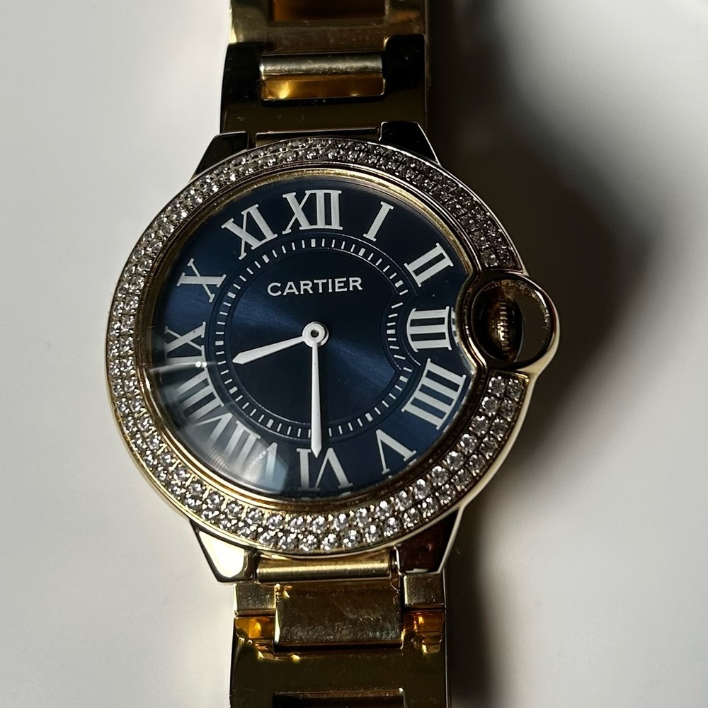 Gold color watch with dark blue face and rhinestones around. New